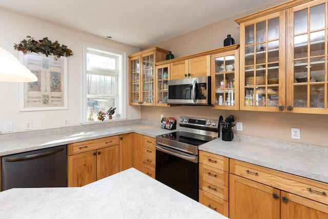 kitchen with light countertops, glass insert cabinets, and appliances with stainless steel finishes