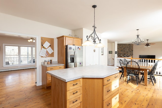 kitchen with light wood-style flooring, stainless steel fridge with ice dispenser, light countertops, ceiling fan with notable chandelier, and baseboard heating