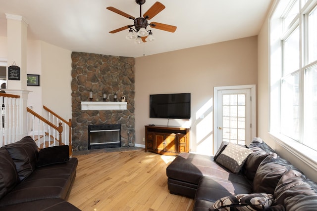 living area featuring a fireplace, stairway, wood finished floors, and ceiling fan