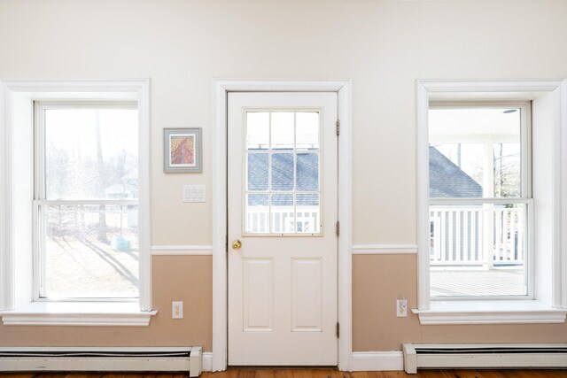 doorway with a wealth of natural light, baseboard heating, a baseboard heating unit, and baseboards