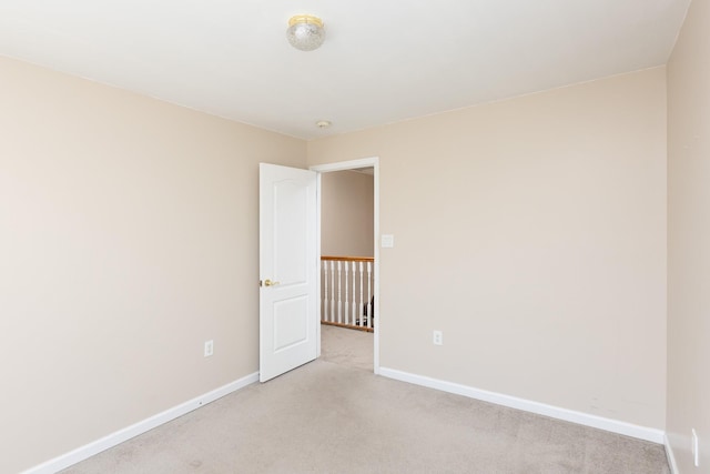 spare room featuring light carpet and baseboards