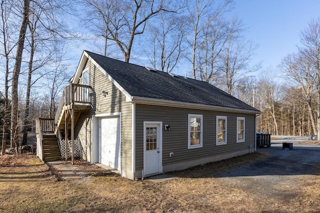 view of side of home featuring stairs and a shingled roof