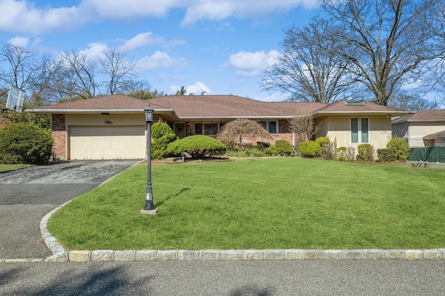 single story home with brick siding, a front lawn, an attached garage, and driveway