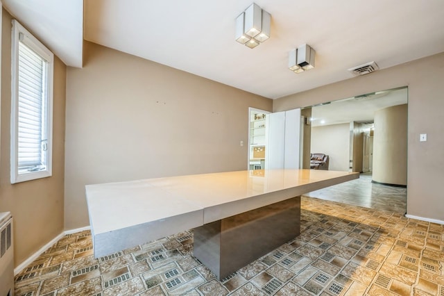 kitchen with stone finish floor, radiator heating unit, baseboards, and visible vents