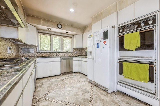 kitchen with tasteful backsplash, white cabinetry, stainless steel appliances, and extractor fan