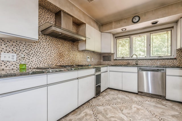 kitchen with backsplash, stainless steel appliances, white cabinetry, wall chimney exhaust hood, and a sink