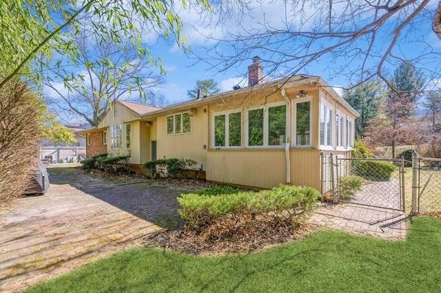 view of front of house featuring a front yard, a gate, fence, and a chimney