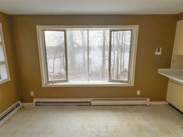 unfurnished dining area featuring tile patterned floors, a wealth of natural light, and baseboard heating