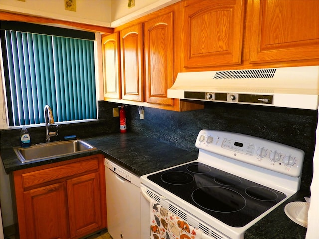 kitchen featuring dark countertops, under cabinet range hood, brown cabinetry, white appliances, and a sink