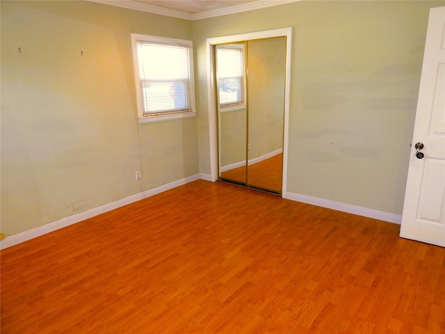 unfurnished bedroom featuring a closet, baseboards, light wood-style floors, and ornamental molding