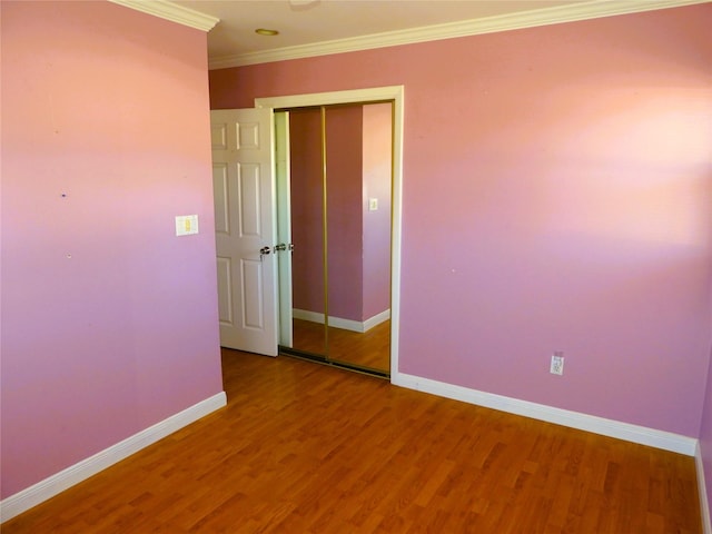 unfurnished room with crown molding, wood finished floors, and baseboards