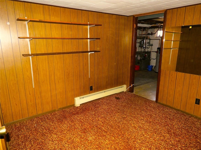 carpeted empty room with a baseboard heating unit and wood walls