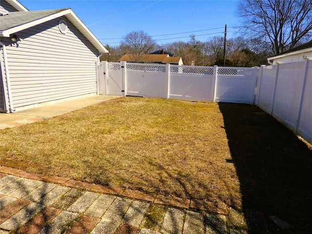 view of yard with a fenced backyard and a gate