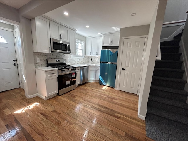 kitchen with decorative backsplash, light wood-style flooring, stainless steel appliances, and light countertops