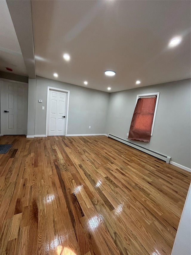 below grade area featuring recessed lighting, wood finished floors, baseboards, and a baseboard radiator