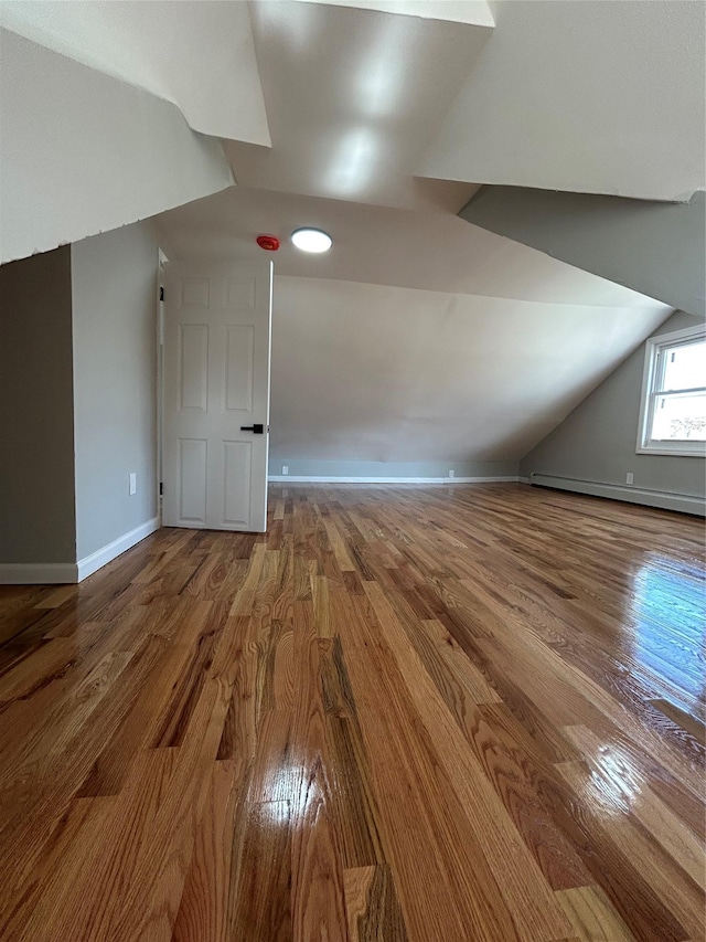 additional living space featuring baseboards, baseboard heating, wood finished floors, and vaulted ceiling