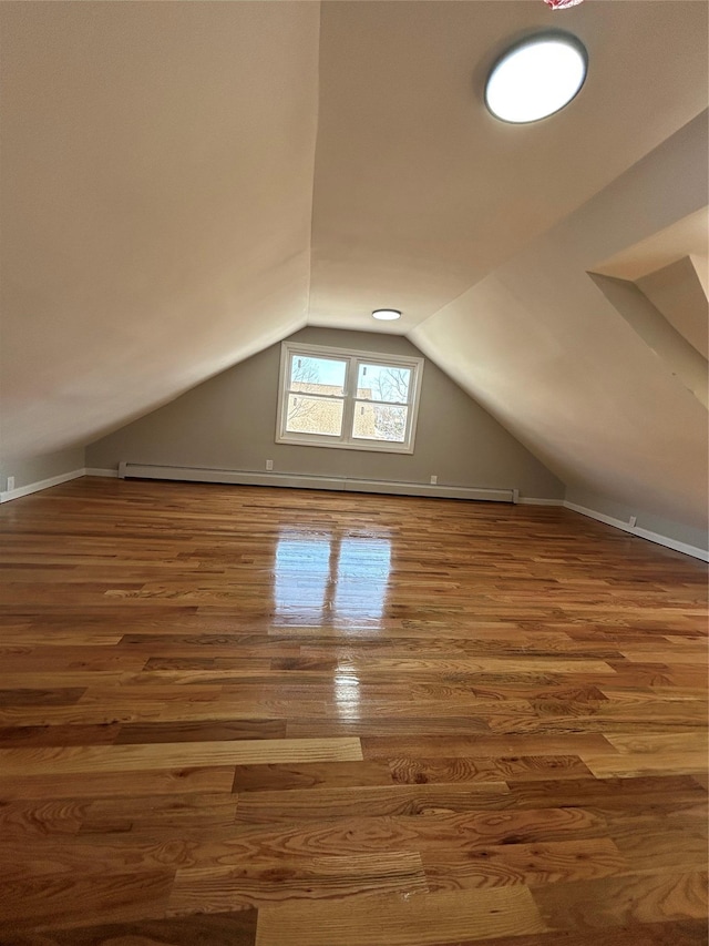 additional living space featuring baseboards, lofted ceiling, and wood finished floors