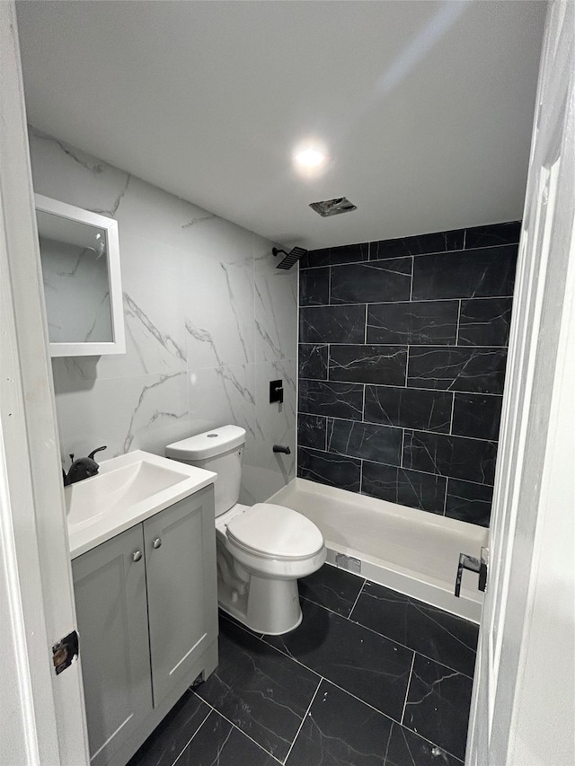 bathroom featuring vanity, toilet, marble finish floor, and tiled shower