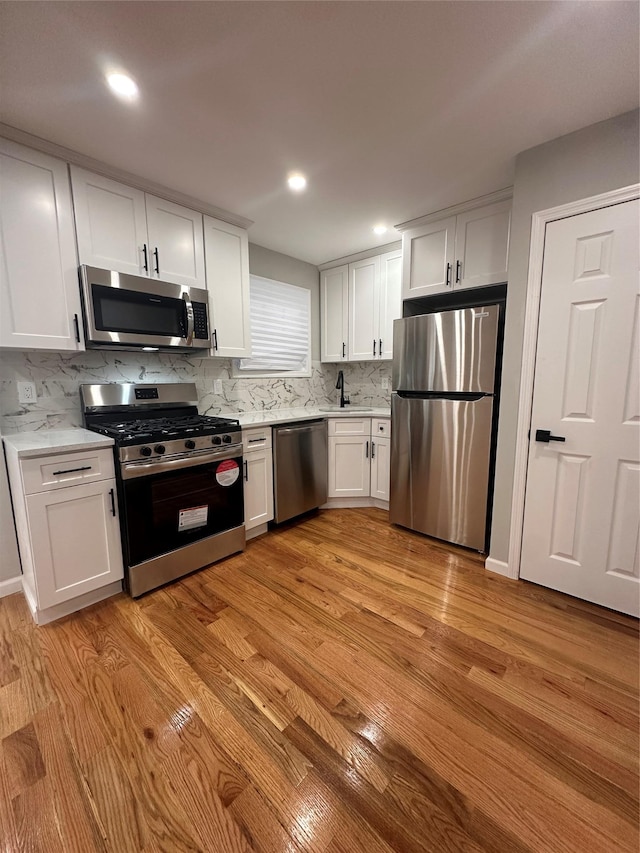 223-45 113th Dr, Queens Village, NY 11429 - kitchen featuring stainless steel appliances, light wood finished floors, white cabinets, tasteful backsplash, and recessed lighting