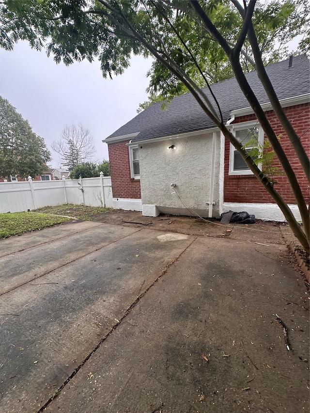 223-45 113th Dr, Queens Village, NY 11429 - view of home's exterior with brick siding, roof with shingles, and a patio