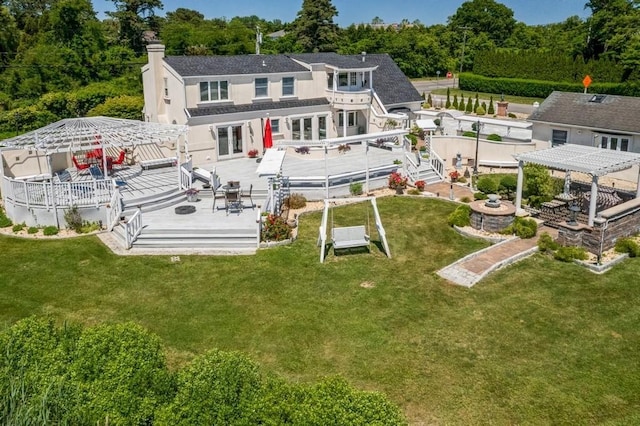 back of property with a pergola, stucco siding, a chimney, a deck, and a lawn