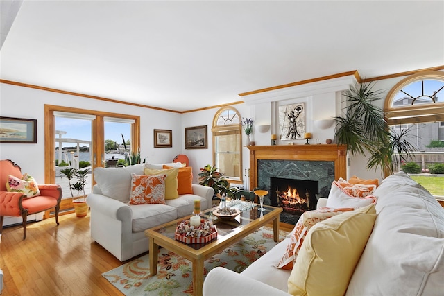 living room featuring light wood-style flooring, ornamental molding, and a premium fireplace