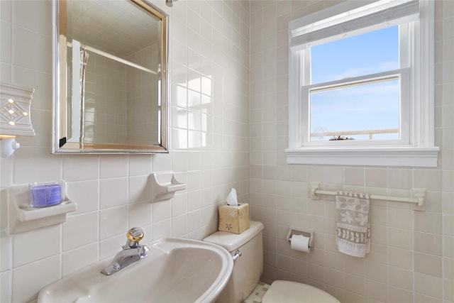 bathroom with a sink, a shower, toilet, and tile walls