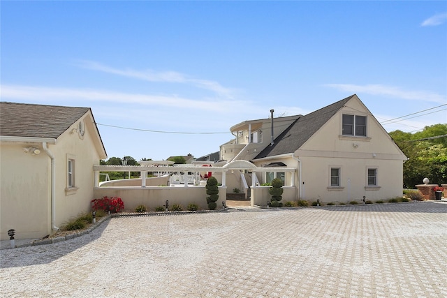 view of side of home featuring fence, roof with shingles, and stucco siding