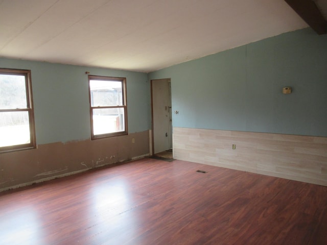 unfurnished room featuring lofted ceiling, wood finished floors, and visible vents