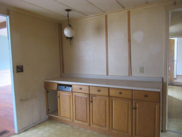 kitchen with visible vents, brown cabinetry, light countertops, light floors, and hanging light fixtures