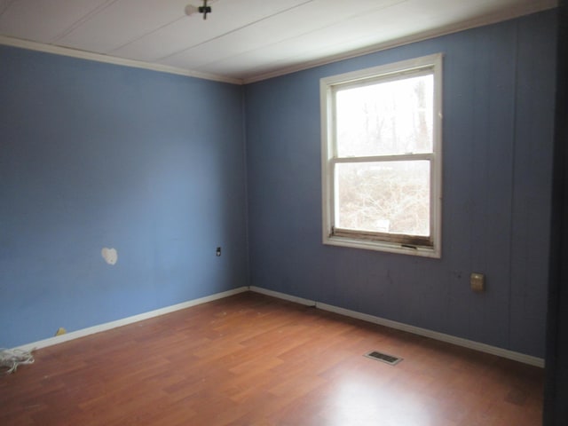 empty room featuring visible vents, baseboards, and wood finished floors