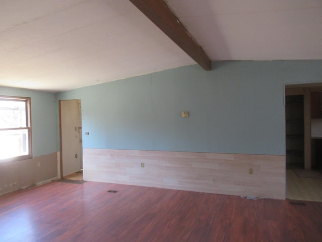 spare room featuring vaulted ceiling with beams and wood finished floors