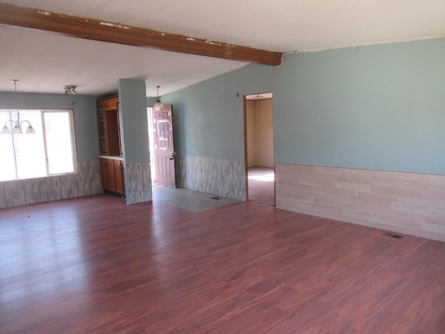 unfurnished room featuring vaulted ceiling with beams, wood finished floors, and a wainscoted wall