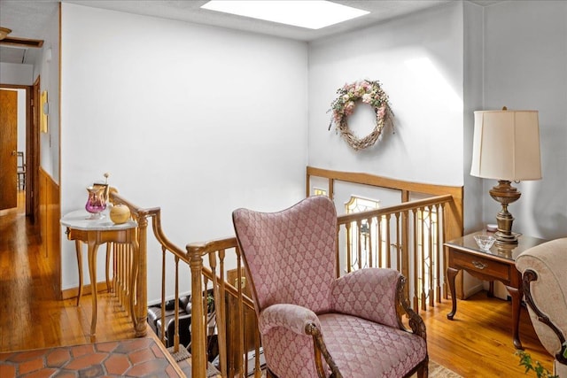 sitting room featuring a skylight, a baseboard heating unit, and wood finished floors