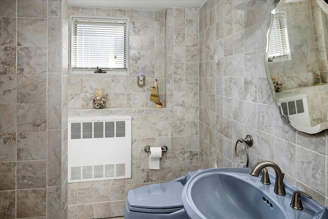 bathroom with radiator, tile walls, and a sink