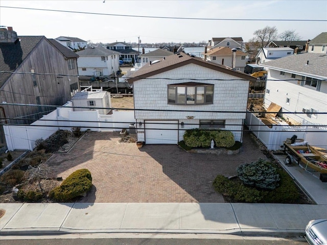 view of front of house featuring a residential view, decorative driveway, a garage, and fence