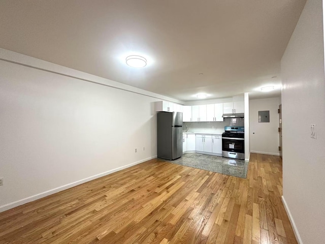 kitchen featuring under cabinet range hood, white cabinetry, stainless steel appliances, light wood-style floors, and baseboards