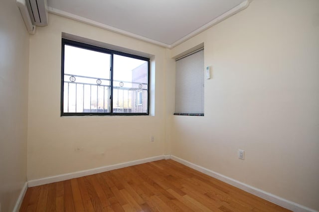 empty room with wood finished floors, baseboards, and a wall mounted AC