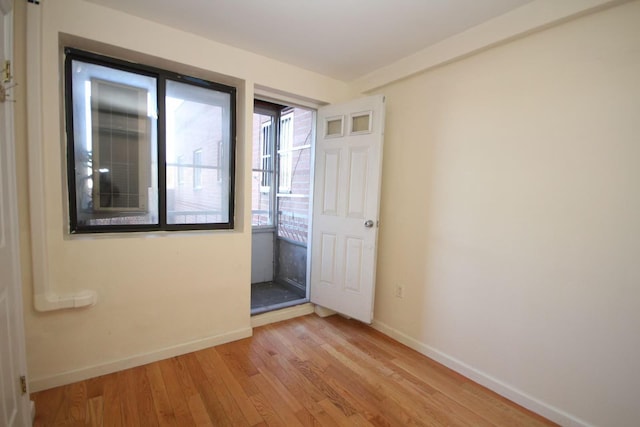 empty room featuring baseboards and light wood finished floors