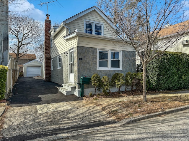 309 S 11th St, New Hyde Park, NY 11040 - view of front of house featuring aphalt driveway, entry steps, a chimney, a garage, and an outdoor structure