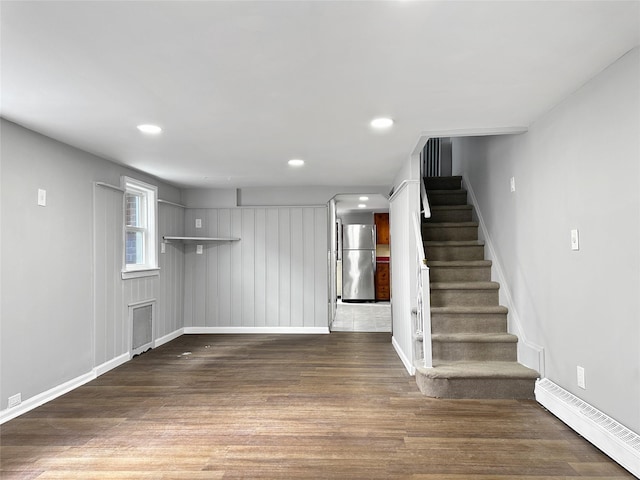 unfurnished living room featuring stairway, wood finished floors, baseboards, recessed lighting, and a baseboard heating unit