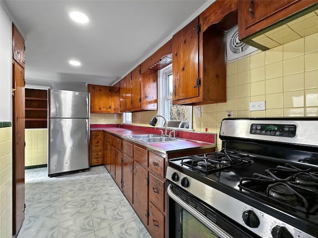 kitchen with decorative backsplash, recessed lighting, brown cabinets, appliances with stainless steel finishes, and a sink