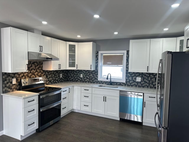 kitchen with dark wood finished floors, a sink, stainless steel appliances, light countertops, and under cabinet range hood