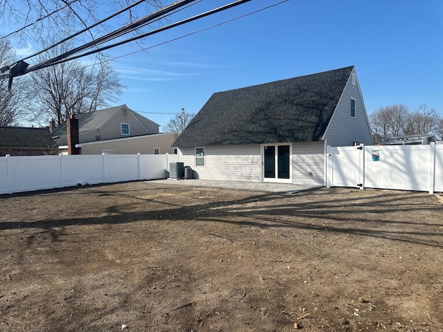 back of property with central air condition unit, a shingled roof, and a fenced backyard