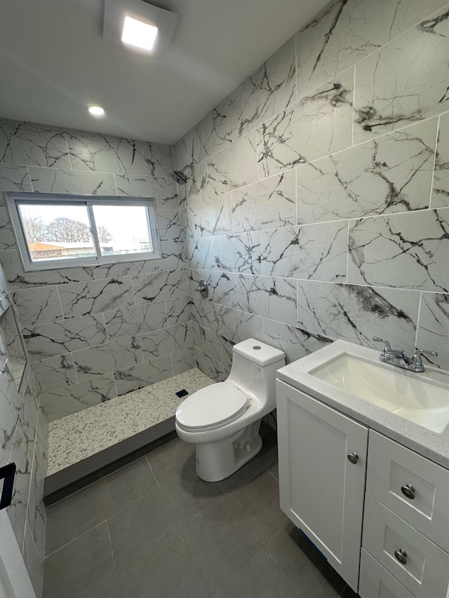 bathroom with tile walls, a stall shower, toilet, and vanity