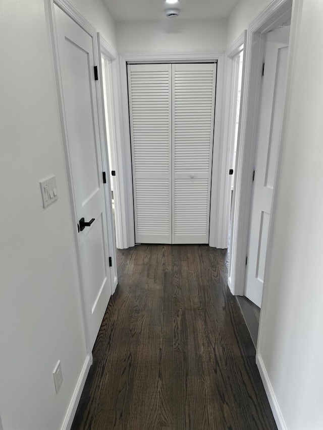 hallway with dark wood finished floors and baseboards