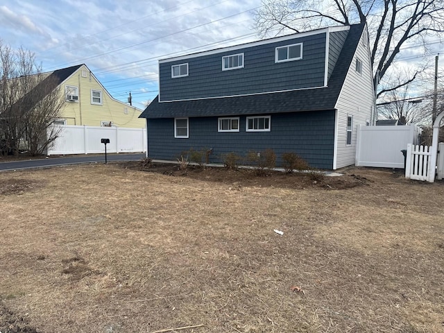 back of property with a shingled roof and fence