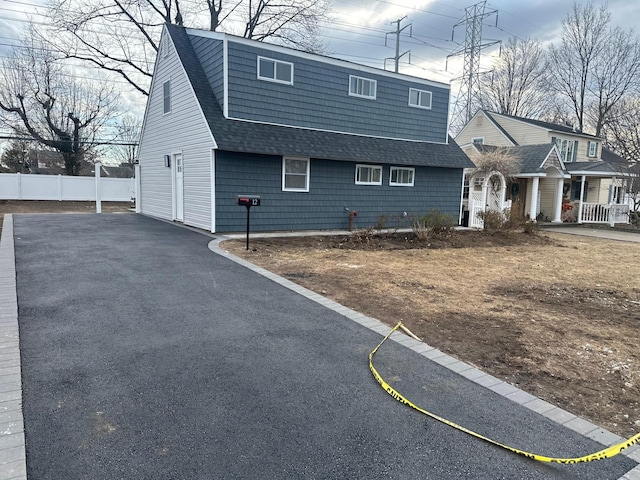 view of front of property featuring roof with shingles and fence