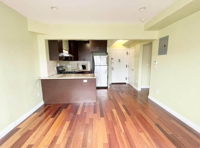 kitchen with electric panel, backsplash, stainless steel appliances, a peninsula, and light countertops