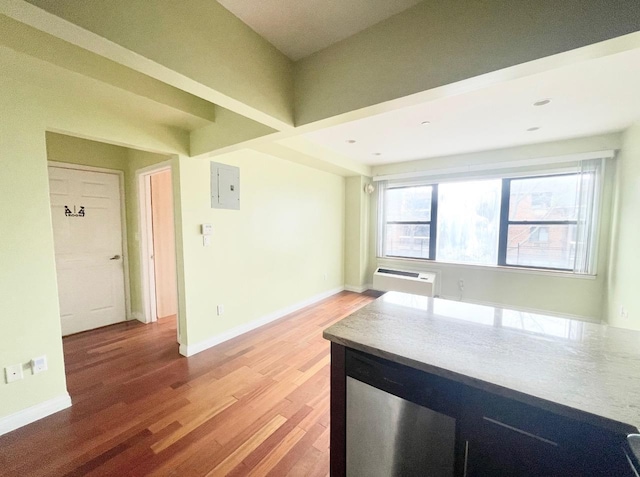 kitchen featuring an AC wall unit, light wood-style flooring, electric panel, and baseboards